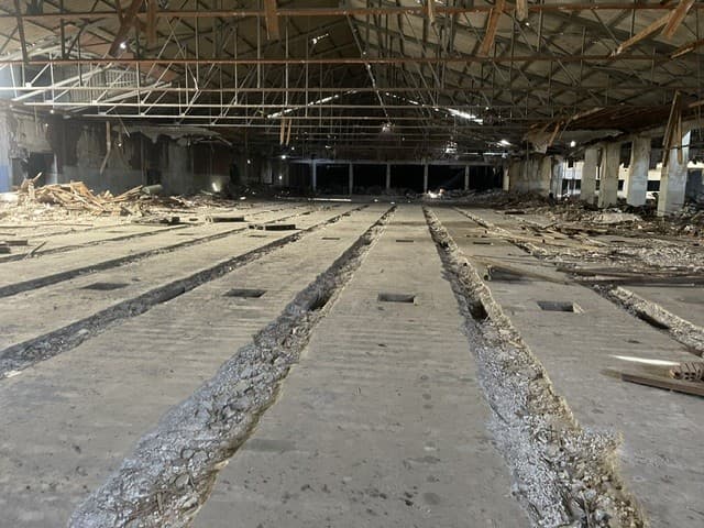 Interior d'una nau industrial enderrocada amb el paviment aixecat